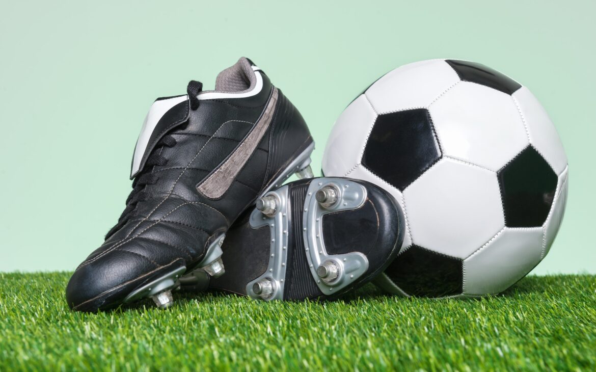 Football or Soccer boots and ball on grass